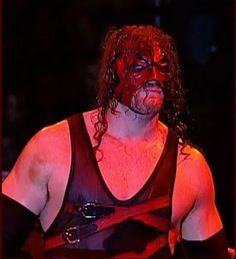 a man with red paint on his face wearing a wrestling outfit and holding a black belt