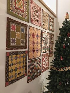 there are many quilts on the wall and a christmas tree is next to it