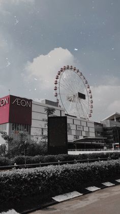 a large ferris wheel sitting next to a tall building with a sky in the background