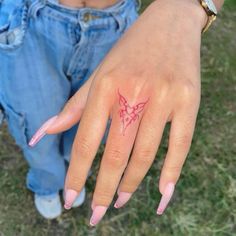 a woman's hand with a butterfly tattoo on her left thumb and pink fingernails