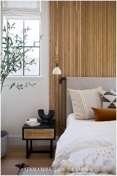 a white bed sitting under a window next to a wooden wall