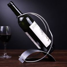 a bottle of wine is sitting on a metal holder with a glass next to it