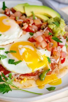 two eggs and avocado are on top of an open - faced tortilla