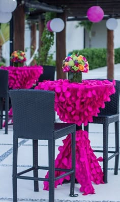 the table is covered with pink ruffles and has two black chairs at it