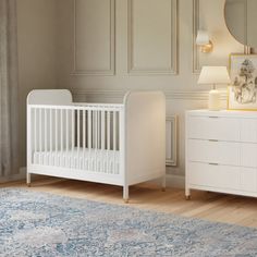 a baby's room with a crib, dresser and mirror on the wall