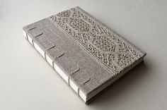 an open book with lace on it sitting on top of a white tablecloth covered surface