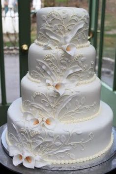 a three tiered white wedding cake sitting on top of a metal table next to a green door