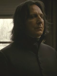 a man with long hair wearing a black shirt and bow tie looking off into the distance