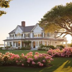 a large white house surrounded by flowers and trees