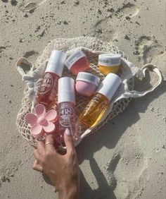 a person is holding several bottles on the beach with their hands in front of them