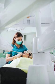 a woman is getting her teeth checked by a dentist