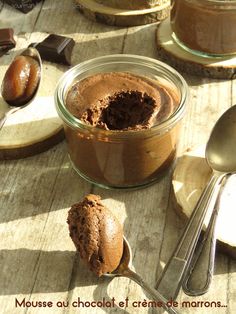 there is a jar of chocolate pudding on the table with spoons next to it