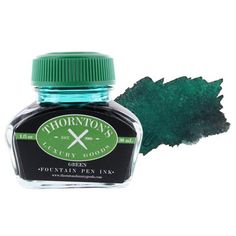 a bottle of green ink with a leaf on the top and one end next to it