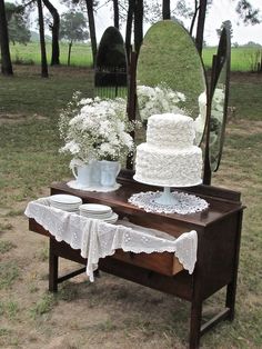 a table with a cake on it in front of a mirror and vases filled with flowers