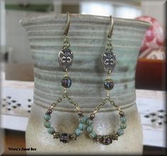 a pair of earrings sitting on top of a vase