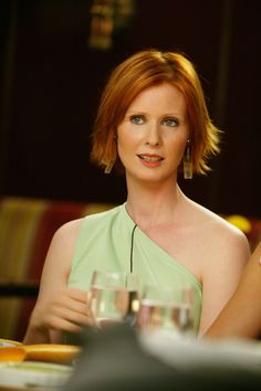 a woman in a green dress sitting at a table with wine glasses on her lap