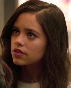 a close up of a person wearing a necklace and looking off to the side with a serious look on her face