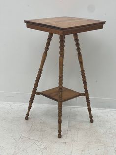 an old wooden table with two legs and a shelf on the top, against a white wall