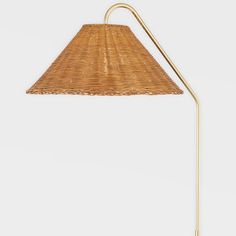 a lamp that is made out of wicker and has a gold metal pole on the side