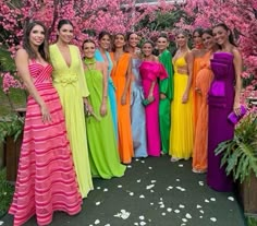 a group of women standing next to each other in front of trees with pink flowers