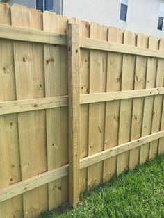 a wooden fence in the grass next to a house