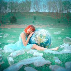 a woman sitting in the grass with a globe on her back