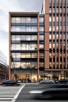 an office building with lots of windows on the side of it and cars driving down the street