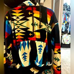 a colorful jacket hanging up on a rack in a room with other clothing and shoes