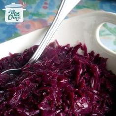 a bowl filled with red cabbage next to a spoon