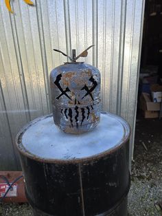 an old metal container sitting on top of a barrel