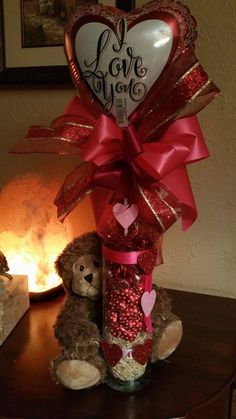 a teddy bear sitting on top of a table next to a vase filled with hearts