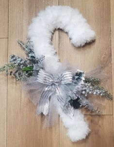 a white wreath with silver decorations on top of a wooden floor