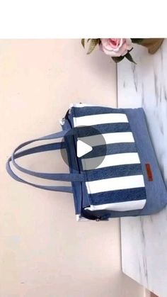 a blue and white striped bag sitting on top of a table next to a flower