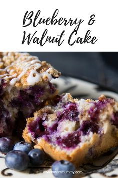 blueberry and walnut cake is cut in half on a plate with fresh blueberries