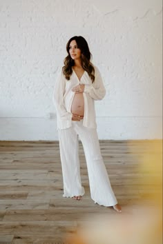 a pregnant woman in white poses for a photo