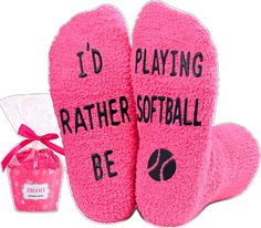 two pink mitts with i'd playing rather softball written on them next to a bag of candy