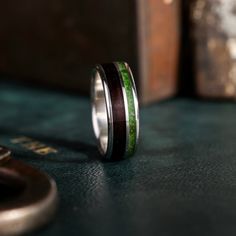 a close up of a wedding ring on a table with a key in the background