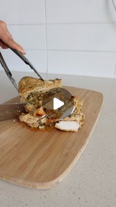 a person cutting up food on top of a wooden cutting board with two large knives