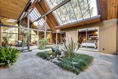 the inside of a house with large windows and lots of plants in front of it