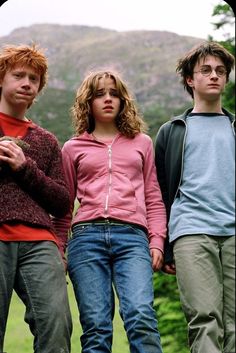 three young people standing next to each other in front of trees and hills with mountains behind them