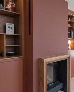 a living room with pink walls and a fire place in the center, surrounded by bookshelves