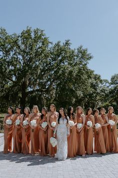 a bride and her bridal party posing for a photo in front of some trees