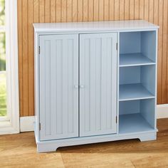 a blue cabinet with two doors and shelves in front of a wooden paneled wall