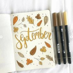 an open notebook with the word november written in gold on it next to three markers