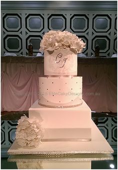 a three tiered wedding cake with flowers on the top and bottom, sitting on a table