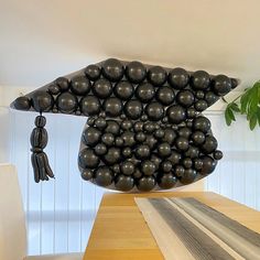 a table topped with lots of black balloons and a wooden dining room table covered in white chairs