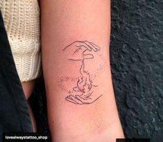 a woman's arm with a tattoo on it that has two hands holding something