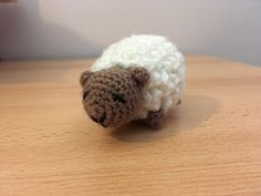 a crocheted sheep sitting on top of a wooden table next to a window