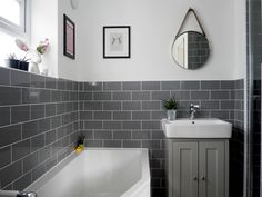 a white bath tub sitting under a bathroom mirror