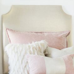 a bed with pink and white pillows on top of it